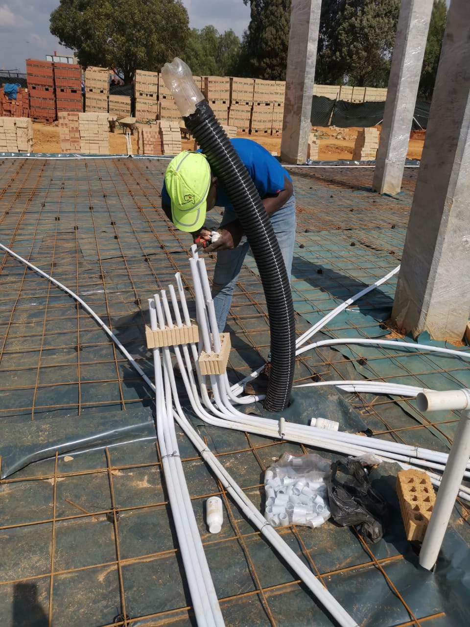 worker laying tubing for electrical wiring at construction site