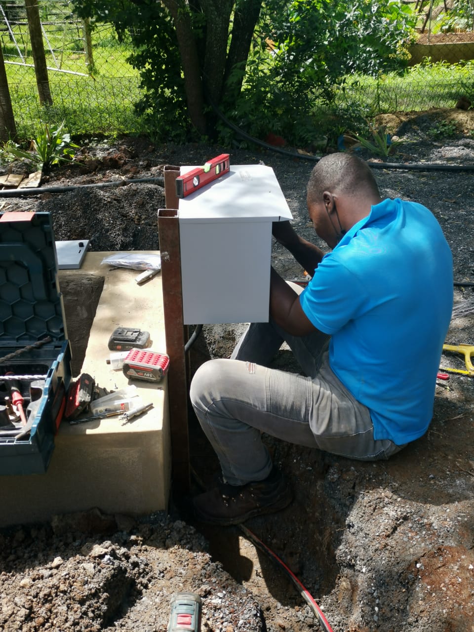 worker installing distribution box for borehole pump motor