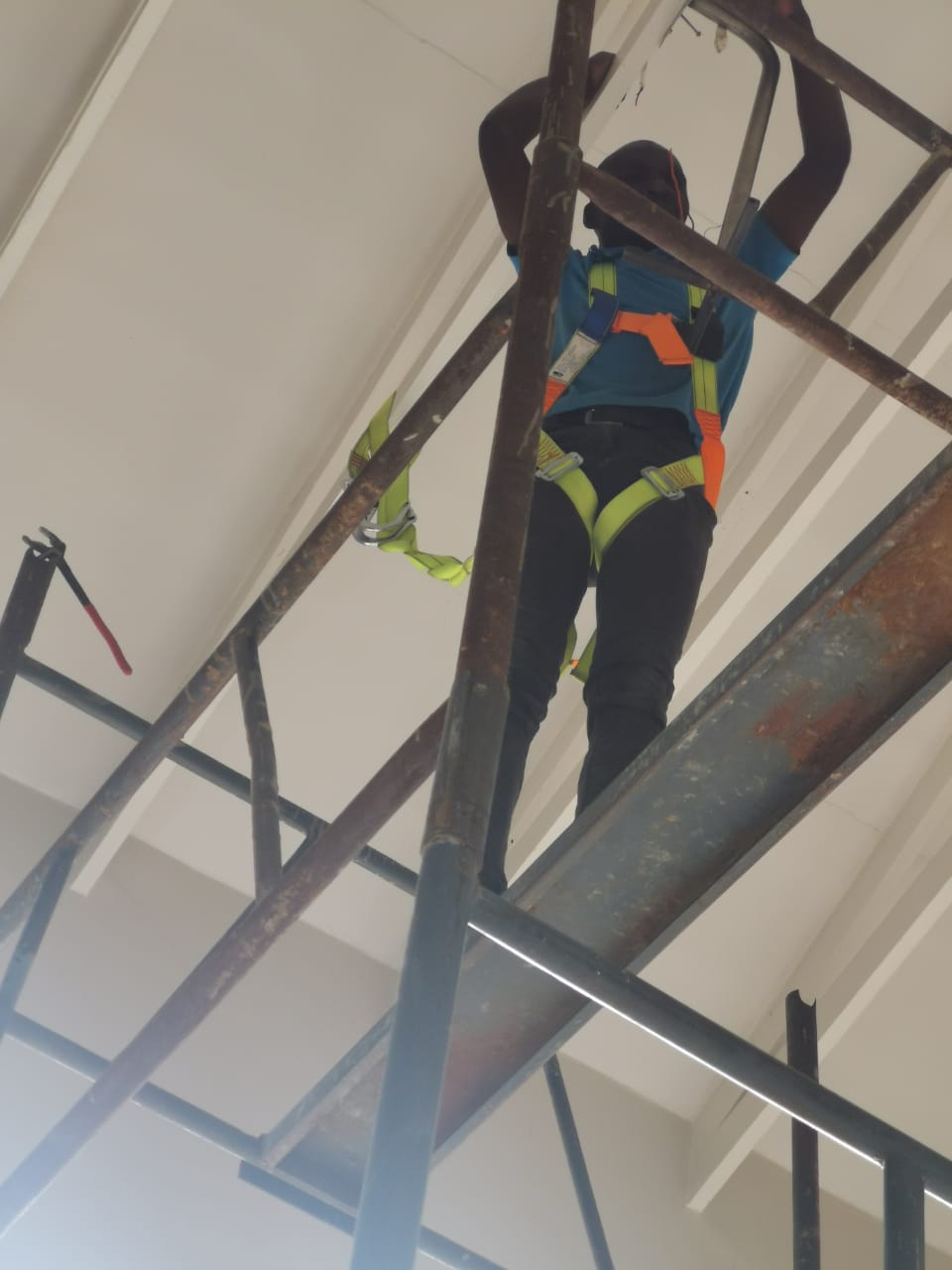 worker on scaffolding installing lighting on high ceiling