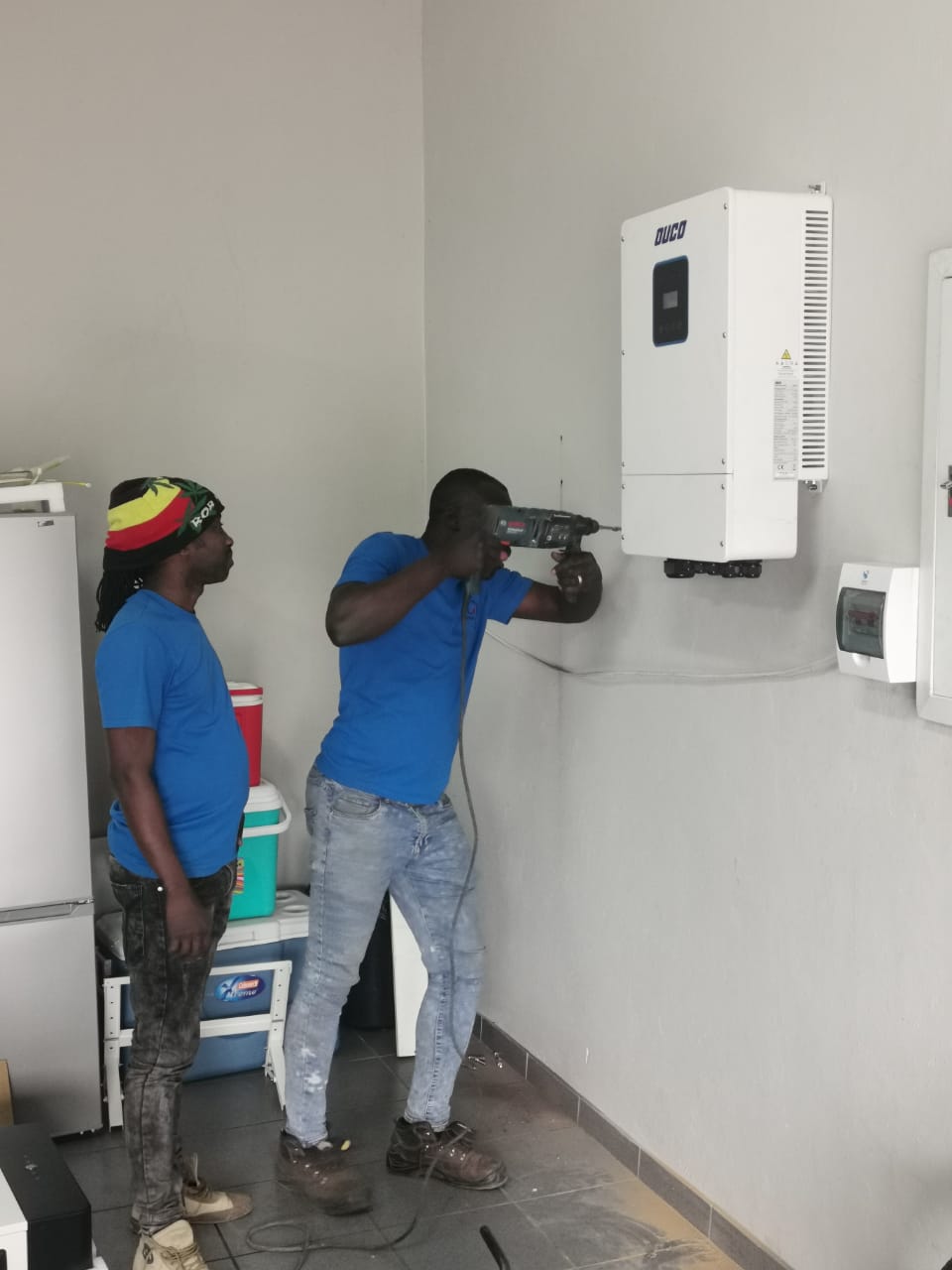 workers drilling wall to mount inverter