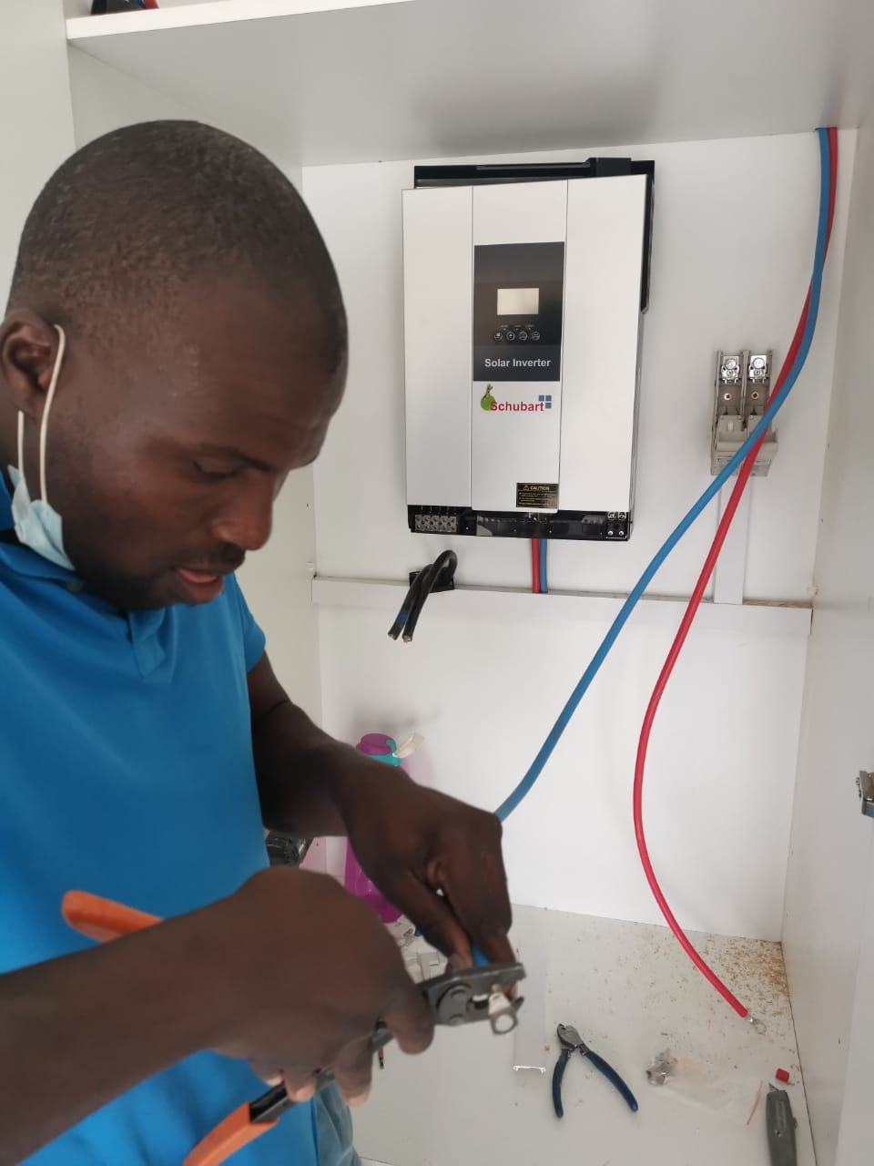 worker with wire cutters connecting solar inverter