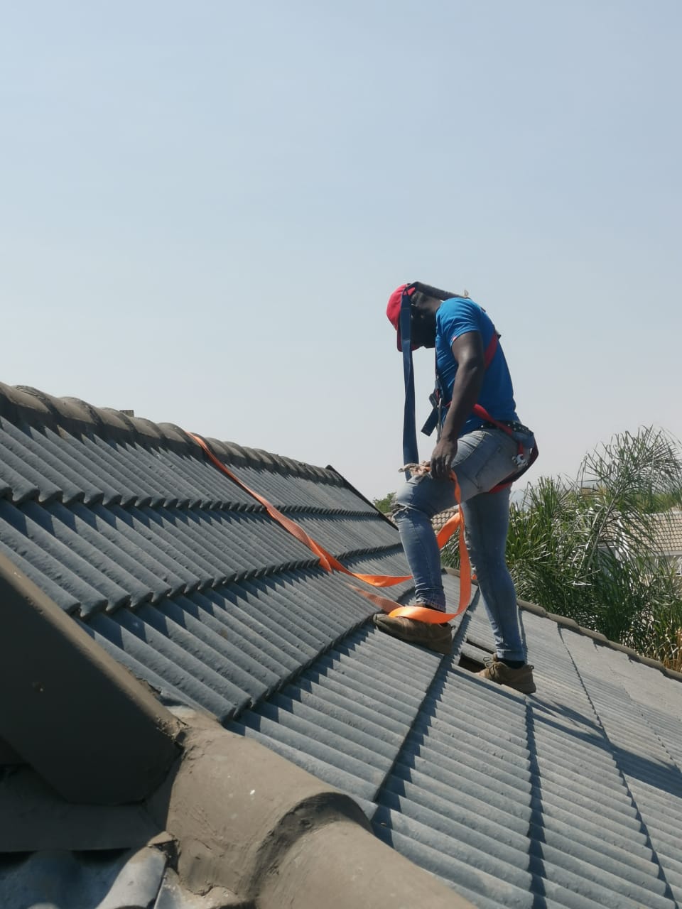 woker on roof with harness installing solar panel