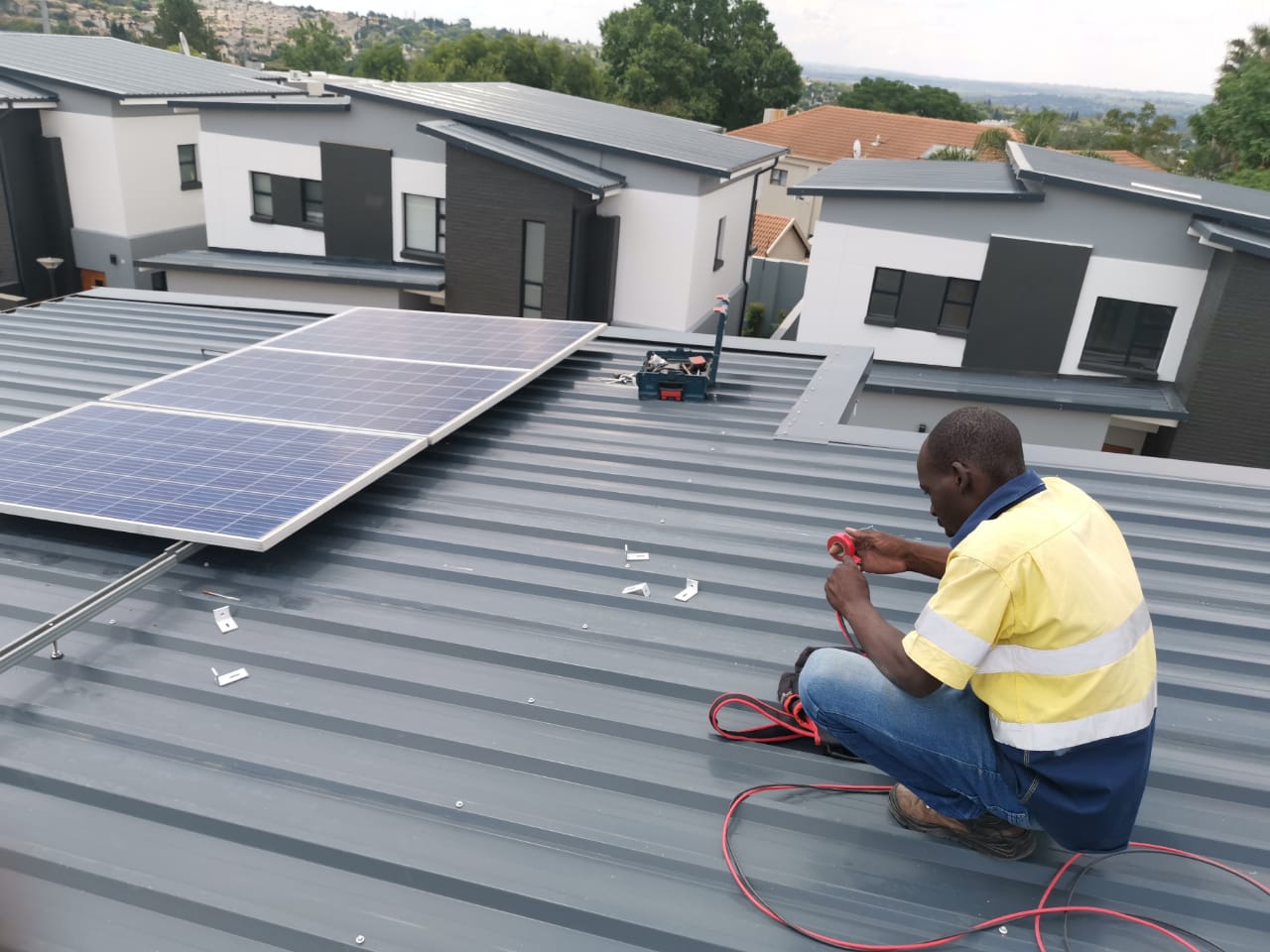 worker installing solar panels on roof